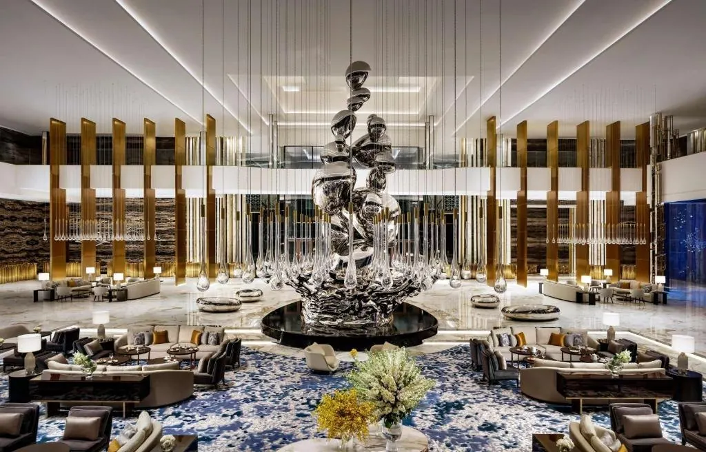 Die Lobby mit ihrer skulpturalen Brunneninstallation — öffentliche Flächen als eigenständige Anziehungspunkte, nicht bloß Durchgang.