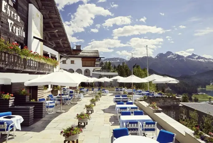Sonnenterrasse eines Bergrestaurants mit weißen Schirmen und Blick über das Tal