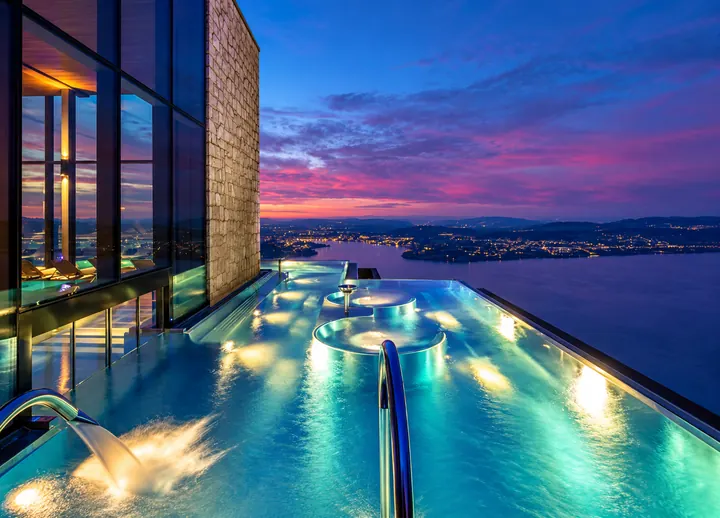 Piscina infinita iluminada sobre el lago de los Cuatro Cantones al anochecer