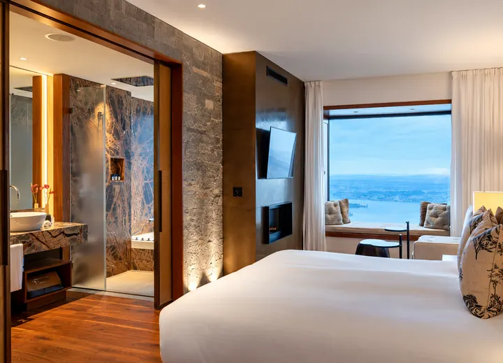 Habitación de hotel con un gran ventanal y vista sobre el lago de los Cuatro Cantones