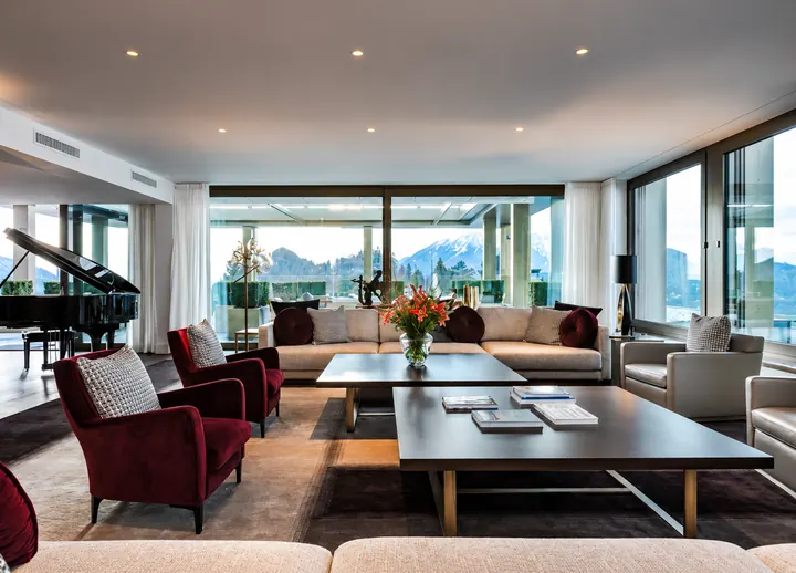 Amplia sala de estar de una residence suite con piano de cola y ventanales panorámicos hacia las montañas