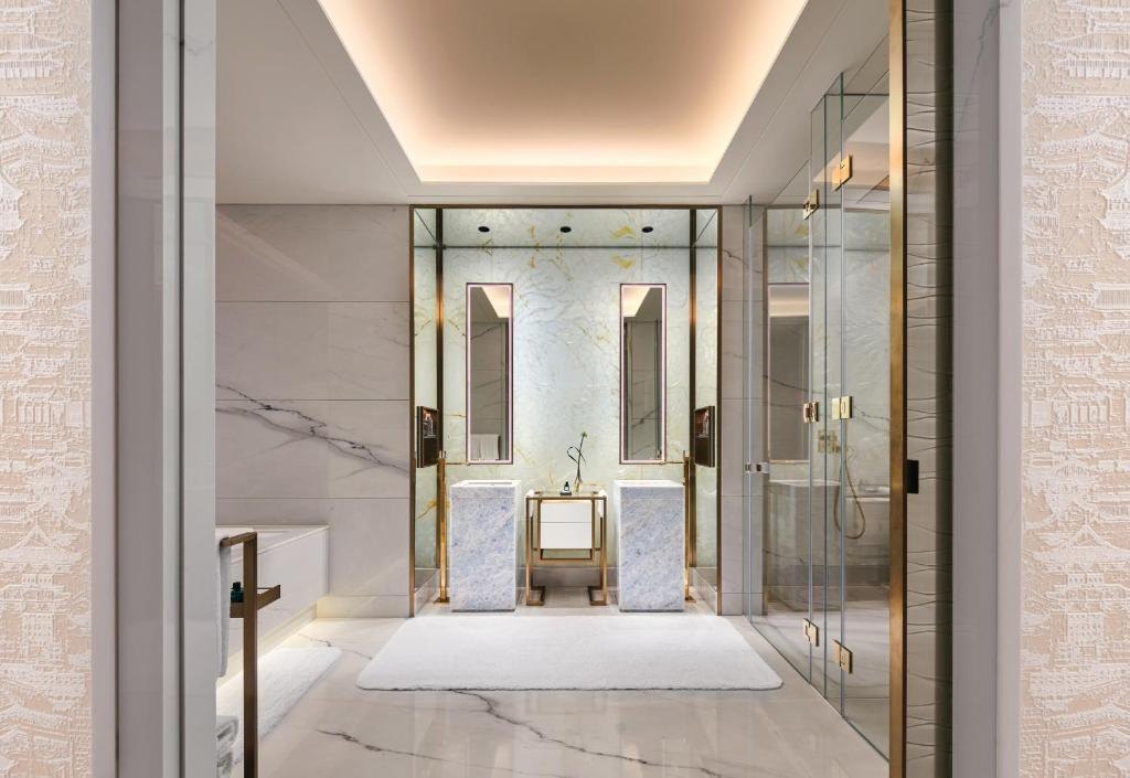 El baño de mármol de una suite — materialidad y artesanía como contrapeso a la fuerza técnica del edificio.