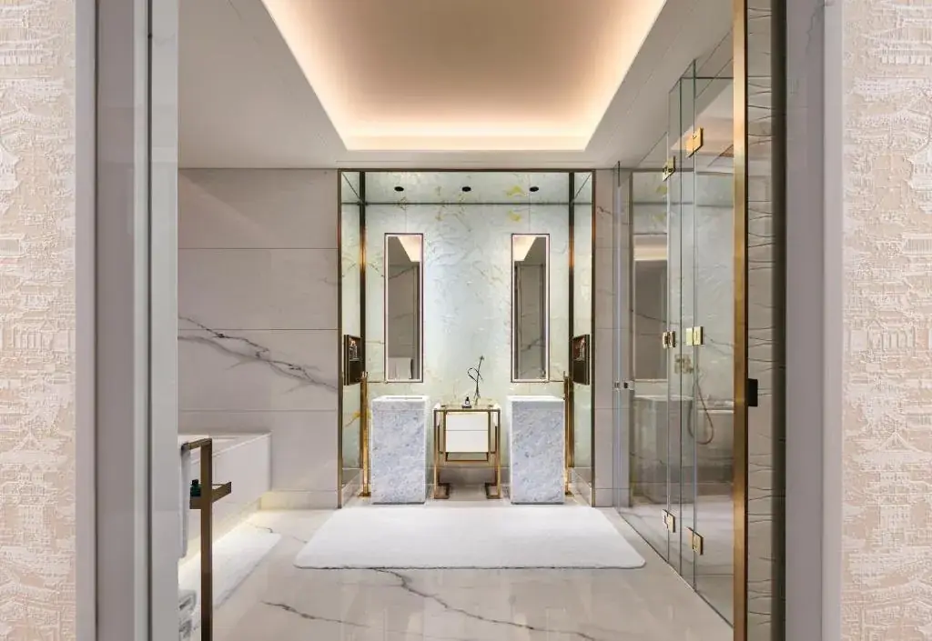 El baño de mármol de una suite — materialidad y artesanía como contrapeso a la fuerza técnica del edificio.