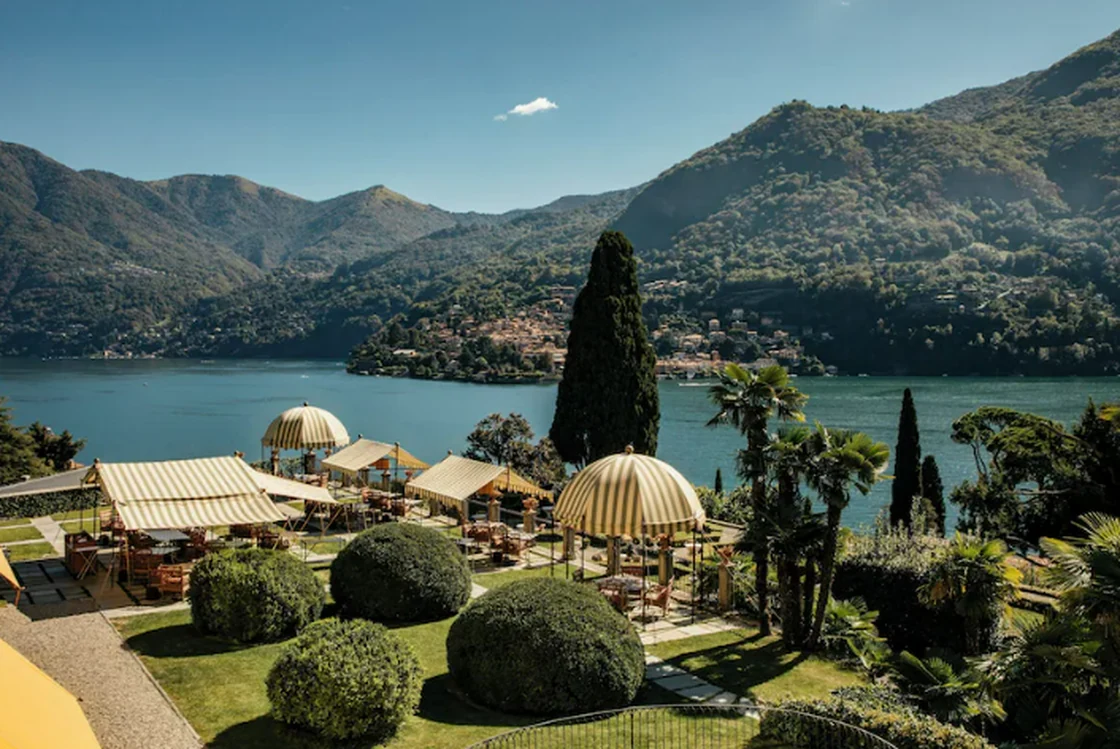 Poolgarten von Passalacqua mit gestreiften Sonnenschirmen und Blick über den Comer See und die Berge