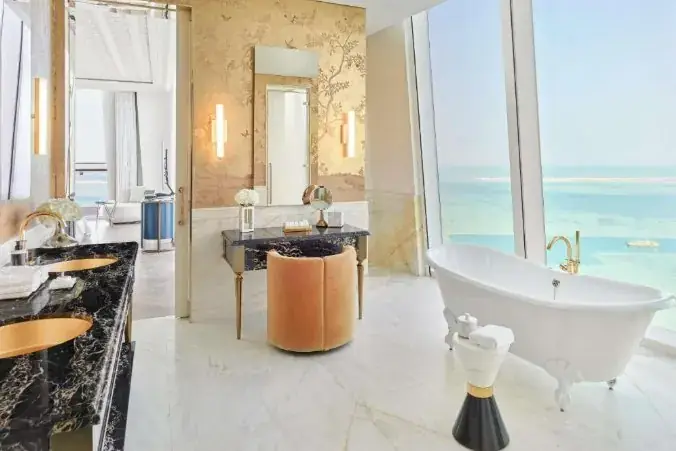 A suite bathroom with a free-standing tub and a view of the Gulf — the experience reaches into the most private spaces.