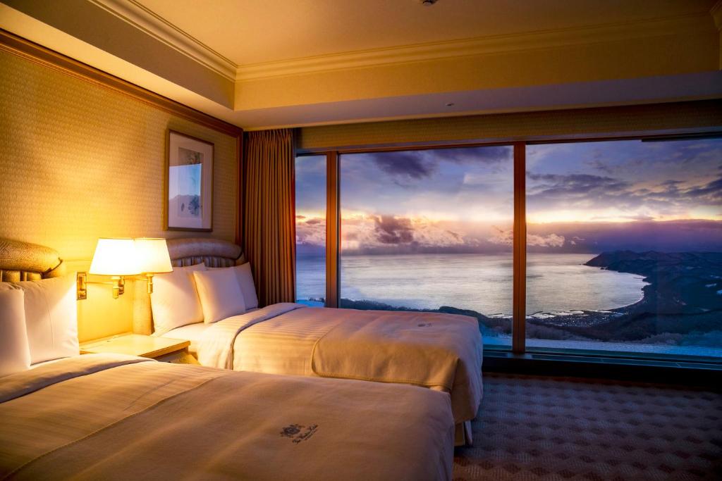 Zimmer mit Panoramablick auf See und Küste im Abendlicht, The Windsor Hotel Toya.