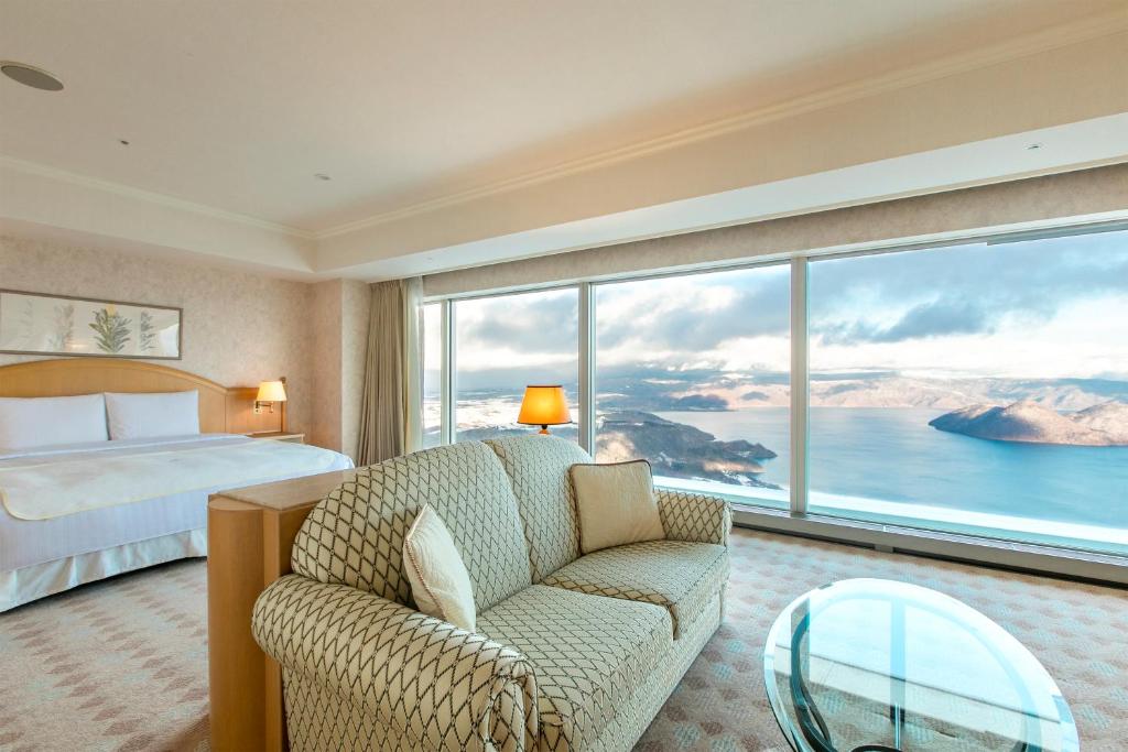 Suite mit Wohnbereich und Panoramafenster zum See, The Windsor Hotel Toya.